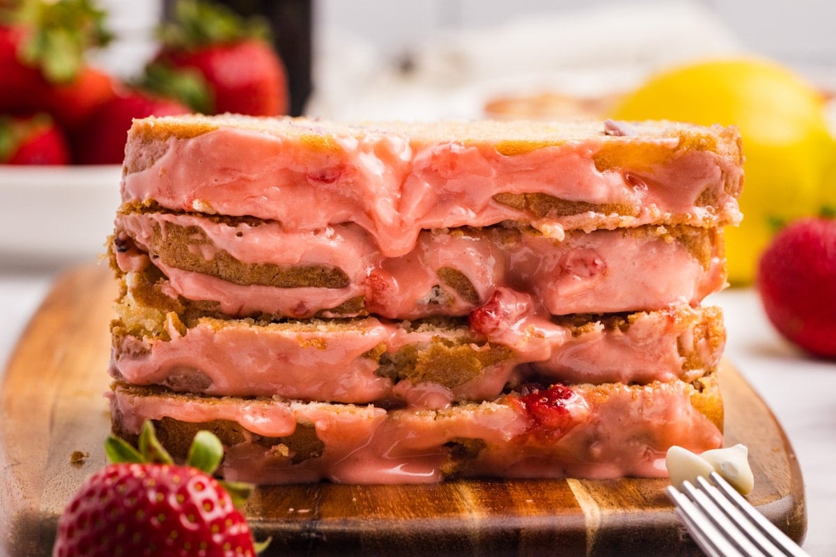 Slices of strawberry bread stacked on a cutting board.