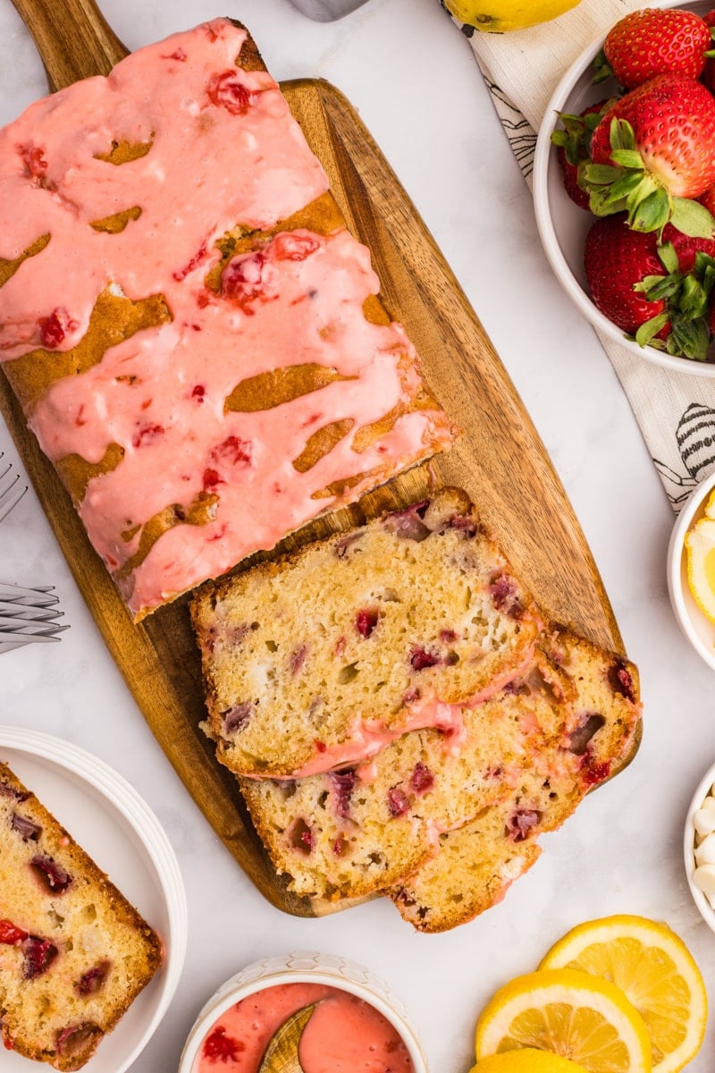 A loaf of strawberry quick bread on a cutting board, cut into slices.